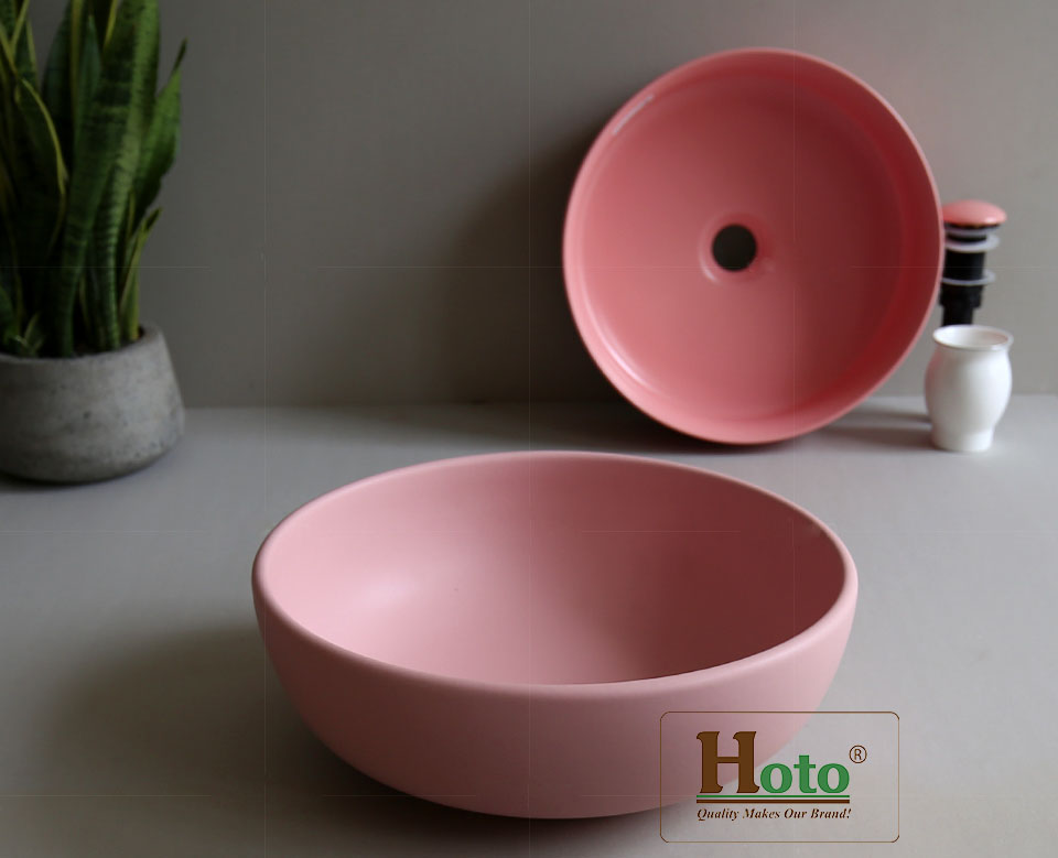 Lavabo sứ màu hồng hình tròn đặt bàn.